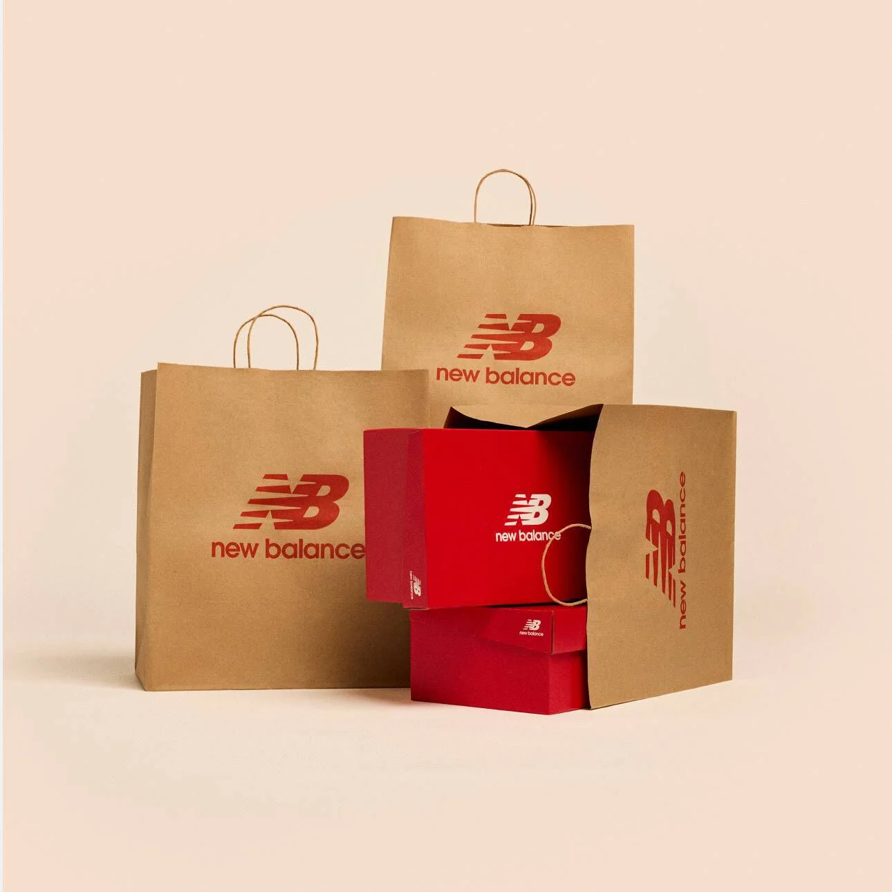 Multiple brown paper New Balance shopping bags on a tan studio backdrop.